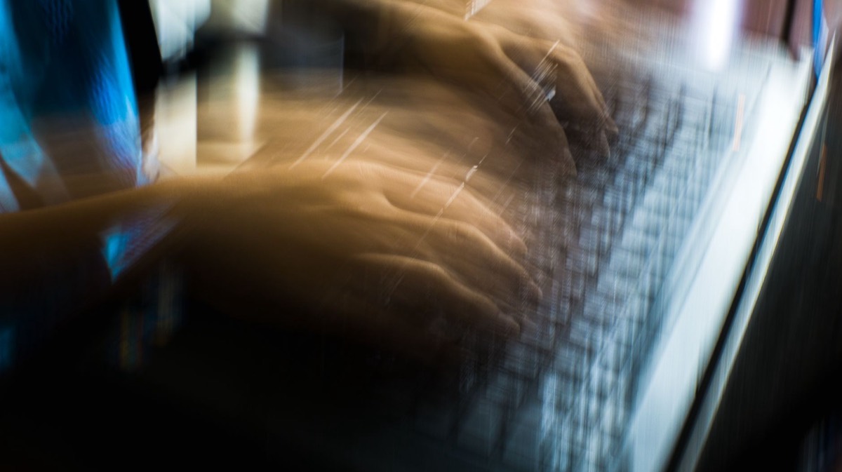 Person typing quickly at a laptop keyboard