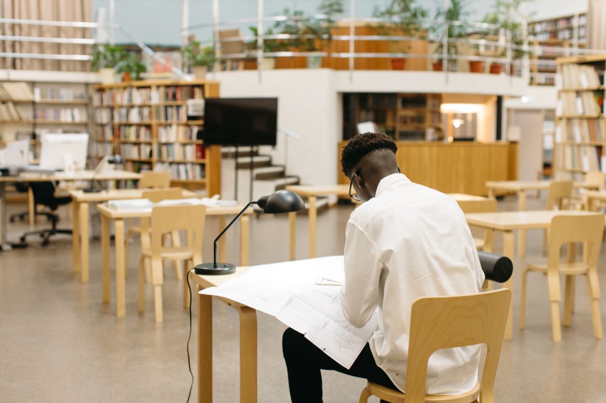 A person reading a book surrounded by shelves of other titles